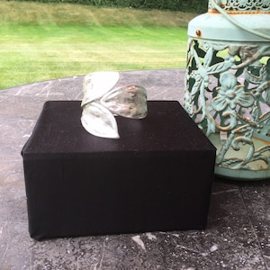 May include: A silver metal cuff bracelet with a leaf design. The bracelet is displayed on a black surface.