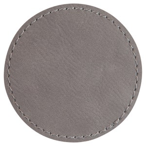 May include: A grey round leather coaster with a stitched edge.