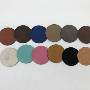 May include: A collection of 12 round coasters in various colours and textures, including cork, wood, leather, and painted finishes.