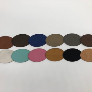 May include: Twelve round, oval-shaped coasters in various colours and textures, including brown, blue, grey, white, turquoise, pink, wood, black, and cork.
