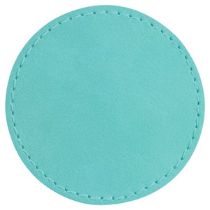 May include: A circular turquoise coaster with a stitched border. The coaster has a smooth surface and a contrasting stitch detail around the edge. The colour is a vibrant, solid turquoise.