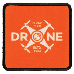May include: Orange square patch with a white drone silhouette and the text "FLYING CLUB" above and "DRONE" below the drone. The text "ESTD. 1984" is below the drone.