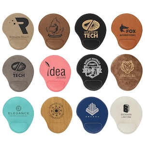 May include: Ten different mousepads with various designs and logos. The mousepads are made of leather and have a brown, black, pink, blue, or white background. The logos include "Robinson Realty", "University", "Weather Tech", "Fox Advertising", "Fantasy Football Champs", "Bengal ILC", "Elegance Day Spa and Salon", "Dandelion", "Encore", and "Bookman Law Firm".