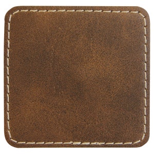 May include: A brown leather coaster with a white stitched border.