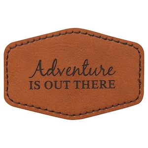 May include: A brown leather patch with stitched edges and the text "Adventure is out there" in black.