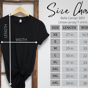 May include: A black short-sleeved t-shirt hanging on a wooden hanger with a size chart for Bella Canvas 3001 unisex jersey t-shirts. The chart lists length and width measurements in inches for sizes XS through 4XL with white arrows.