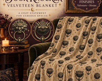 May include: A beige blanket featuring a repeating pattern of dark, metallic-toned door knockers shaped like mythical creatures, interspersed with small gold stars and crescent moons. The fabric has a soft, plush texture throughout.