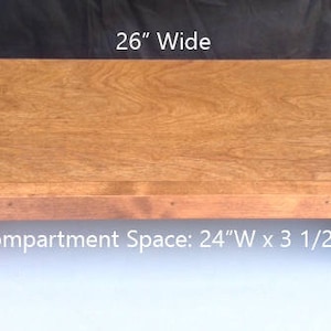 May include: A wooden table with a compartment space. The table is 26 inches wide and the compartment space is 24 inches wide by 3 and 1/2 inches high.