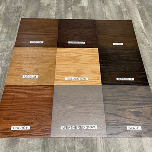 May include: Nine wood stain samples in various shades of brown, gray, and black. The samples are labeled with the following names: Coffee, Espresso, Dark, Medium, Golden Oak, Midnight, Cherry, Weathered Gray, and Slate.