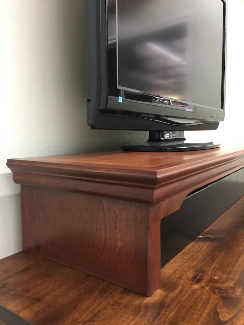 May include: A dark wood TV stand with a black drawer and a raised lip to hold a TV. The stand is made of solid wood and has a traditional design.