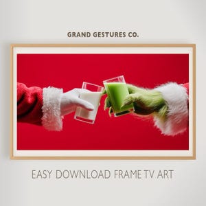 Puede incluir: Impresión enmarcada con fondo rojo. La mano de Papá Noel, con un guante blanco, choca con la mano del Grinch, sosteniendo bebidas en vasos. Los textos "GRAND GESTURES CO." y "EASY DOWNLOAD FRAME TV ART" son visibles.