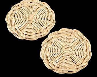 May include: Two round woven wicker coasters in a light beige color. The coasters have a circular pattern and are made of natural materials.