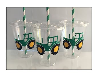 Puede incluir: Tres vasos de plástico transparentes con diseños de tractores verdes y amarillos y pajitas rayadas blancas y verdes.