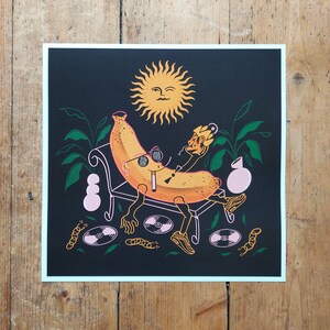 Op de afbeelding: Een gele banaan met een zonnebril en een hoed, die op een bankje ligt met een sigaret in zijn mond. De banaan is omringd door planten, een zon en platen.