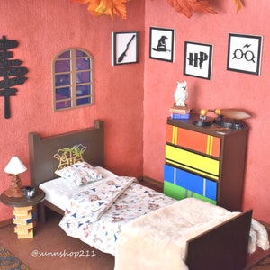 May include: A miniature bedroom set with a brown bed, a white comforter, and a dresser with colorful drawers. The walls are painted red and decorated with black and white Harry Potter themed artwork. The room also features a small lamp, a side table, and a window.