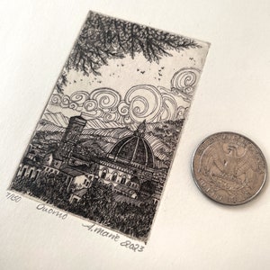 May include: A black and white etching of the Duomo in Florence, Italy, with a quarter for scale. The artwork includes the text "Duomo" and the artist's signature, "A. Mane 2023". The print is numbered 7/150.