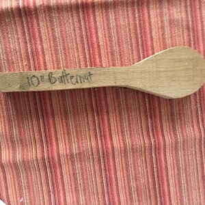May include: A 10-inch wooden spoon made of butternut wood. The spoon is unfinished and has a natural wood color.