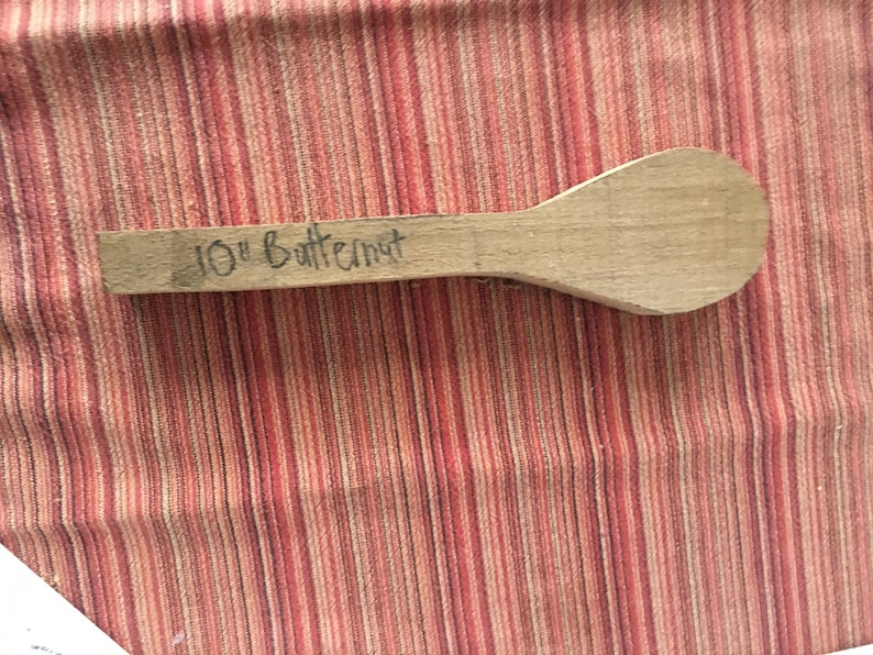 May include: A 10-inch wooden spoon made of butternut wood. The spoon is unfinished and has a natural wood color.