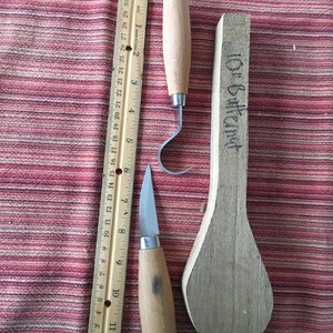 May include: Two wood carving tools with wooden handles and a wooden spoon blank labeled "10" Butternut".