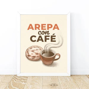 May include: A framed print featuring the words "AREPA con CAFÉ" in orange and brown. The image includes a brown arepa and a steaming brown coffee cup. The background is a light beige color.