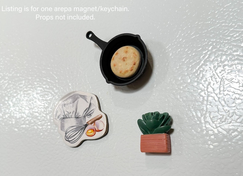 May include: A collection of miniature magnets and keychains. Includes a black skillet with an arepa, a chef's hat with a whisk and eggs, and a green succulent in a terracotta pot. These are perfect for decorating refrigerators or lockers.