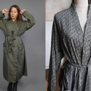 May include: A black and white patterned robe with a long sleeve and a tie belt. The robe has a V-neck and a geometric pattern.