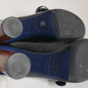 Pode incluir: Sapatos de salto alto de verniz preto com acabamento azul e saltos de madeira. Os sapatos t&ecirc;m uma sola texturizada e o nome da marca "Sonia Rykiel" est&aacute; impresso na sola.