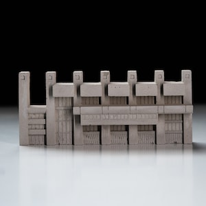 May include: A grey concrete model of a building with multiple windows and a flat roof. The model is made of small, rectangular blocks.