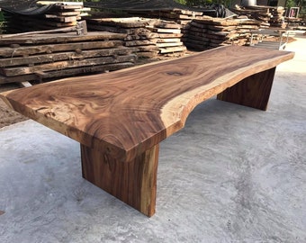 Op de afbeelding: Een grote, rustieke houten tafel met een live edge blad en twee stevige poten. De tafel is gemaakt van een rijk bruin hout met een natuurlijke, organische afwerking.