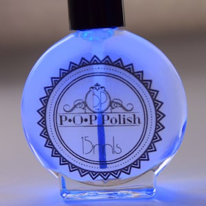 May include: A round bottle of P.O.P Polish nail polish, filled with a bright blue liquid. The label features a circular design with the brand name and the text "15 mls". The bottle has a black cap and a clear, rounded base.