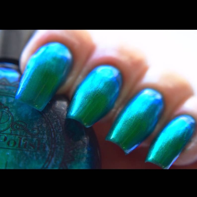 K&ouml;nnte beinhalten: Nahaufnahme von vier Fingern&auml;geln, die mit einem schillernden teal- und gr&uuml;nen Nagellack lackiert sind. Die N&auml;gel sind lang und oval geformt, mit einem gl&auml;nzenden Finish. Die Nagellackflasche ist im Hintergrund zu sehen.