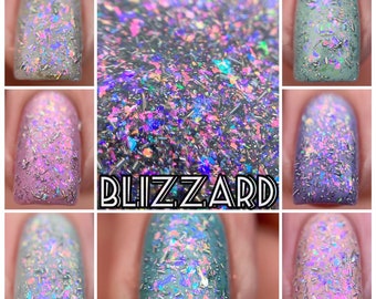 May include: Close-up of several manicured nails showcasing a nail polish with iridescent, glittery flakes. The polish appears in various pastel shades, including lavender, mint green, and pink. The word "BLIZZARD" is displayed in a bold, stylized font.