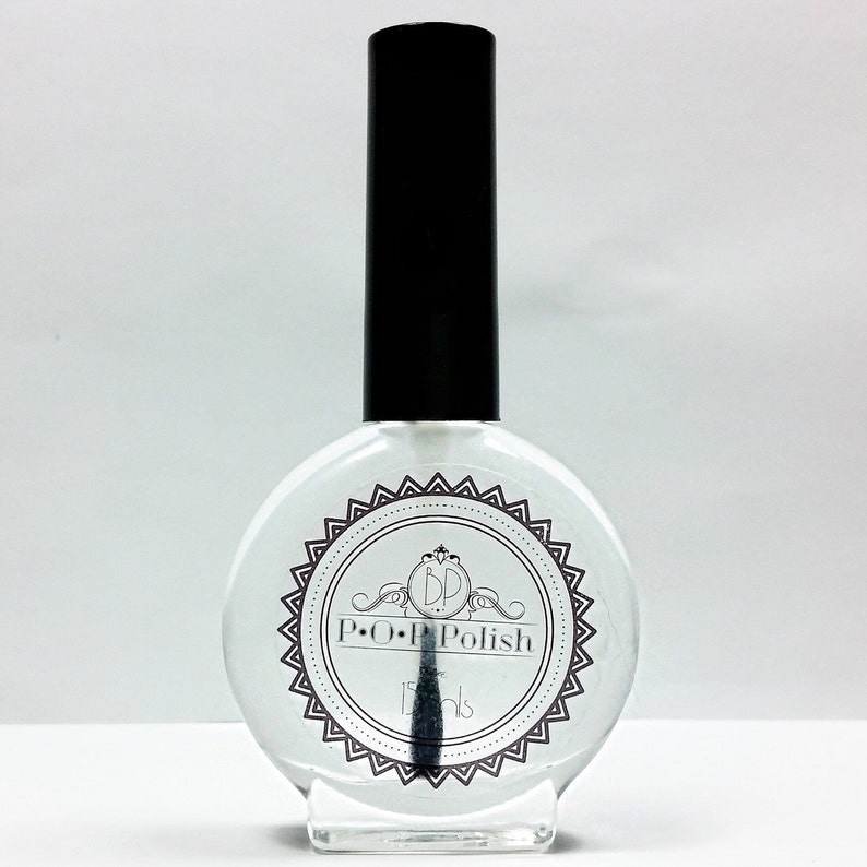 May include: Clear nail polish bottle with a black cap. The bottle has a round shape and a label with the text "P.O.P Polish" and "15 ml". The brush is visible inside the bottle.