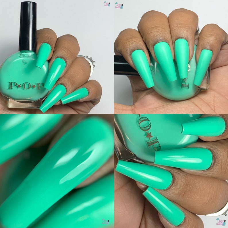 May include: A bottle of teal nail polish with a black cap next to long, teal-colored acrylic nails. The nail polish bottle has the word "POP" printed on it. The nails are a solid, matte color.