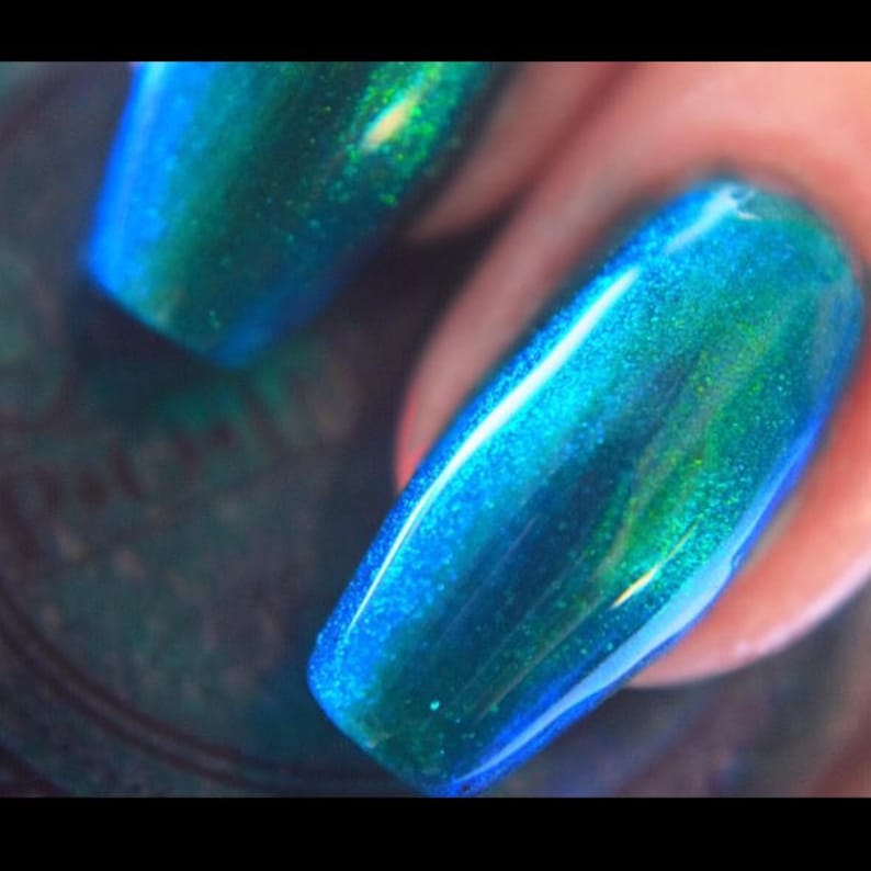 K&ouml;nnte beinhalten: Nahaufnahme eines Fingernagels mit einem leuchtenden, schimmernden teal Nagellack. Der Lack hat ein gl&auml;nzendes Finish mit blauen und gr&uuml;nen Akzenten, wodurch ein mehrdimensionaler Effekt entsteht. Der Nagel ist gut manik&uuml;rt und reflektiert Licht.