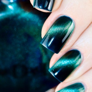 May include: Close-up of manicured nails with a gradient effect. The nails transition from a deep teal at the base to a shimmering green at the tips. The polish has a glossy finish, reflecting light and creating a captivating visual.