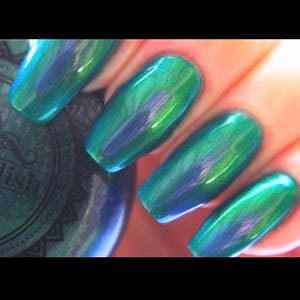 K&ouml;nnte beinhalten: Nahaufnahme von manik&uuml;rten N&auml;geln mit einem schimmernden teal-gr&uuml;nen Lack. Die N&auml;gel sind lang und oval geformt und reflektieren das Licht, um einen schimmernden Effekt zu erzeugen. Der Lack scheint farbver&auml;ndernd zu sein.