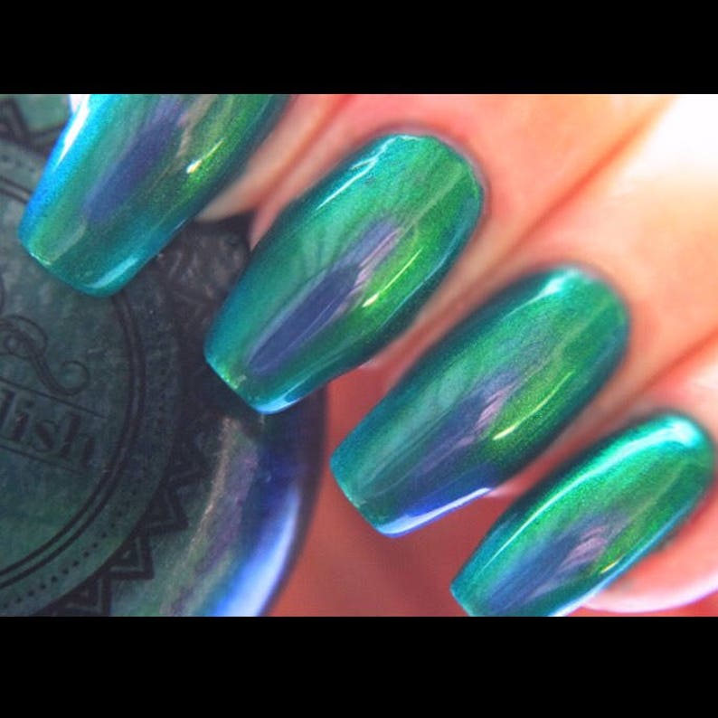 K&ouml;nnte beinhalten: Nahaufnahme von manik&uuml;rten N&auml;geln mit einem schimmernden teal-gr&uuml;nen Lack. Die N&auml;gel sind lang und oval geformt und reflektieren das Licht, um einen schimmernden Effekt zu erzeugen. Der Lack scheint farbver&auml;ndernd zu sein.