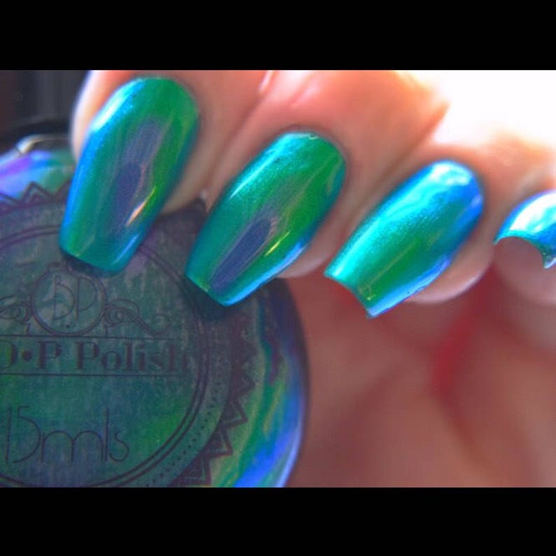 K&ouml;nnte beinhalten: Nahaufnahme von manik&uuml;rten N&auml;geln, die mit einem leuchtenden, schillernden t&uuml;rkisblauen Nagellack lackiert sind. Der Lack wechselt zwischen Gr&uuml;n- und Blaut&ouml;nen und erzeugt einen schimmernden Effekt. Eine Flasche O.P.I-Nagellack ist im Hintergrund teilweise sichtbar.