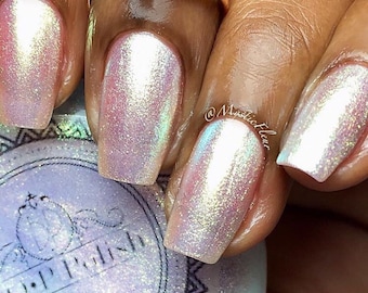 May include: Close-up of iridescent nail polish on several fingernails. The polish has a pearlescent, shimmering effect with hues of pink, white, and a hint of green. The nails are well-manicured and reflect light.
