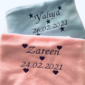 以下が含まれることがあります： 星と「Yahya」という名前と「26.02.2021」という日付が書かれた薄い青色のベビー毛布と、ハートと「Zareen」という名前と「24.02.2021」という日付が書かれたピンク色のベビー毛布の2枚のパーソナライズされたベビー毛布。
