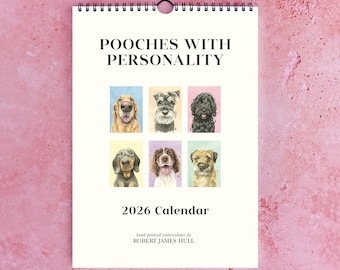 May include: A spiral-bound calendar titled "Pooches With Personality" featuring watercolor portraits of various dog breeds. The 2026 calendar includes images of a golden retriever, schnauzer, and other dogs. The artist's name, Robert James Hull, is printed at the bottom.