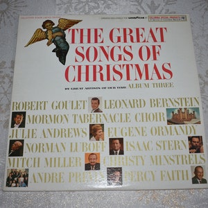 May include: A white vinyl record album cover with a red title "The Great Songs of Christmas" and a picture of an angel. The album features a collection of Christmas songs by artists including Robert Goulet, Leonard Bernstein, Mormon Tabernacle Choir, Julie Andrews, Eugene Ormandy, Norman Luboff, Isaac Stern, Mitch Miller, Christy Minstrels, Andre Previn, and Percy Faith.
