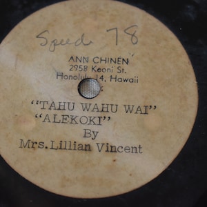 May include: A vintage 78 RPM record label with the title "TAHU WAHU WAI" and "ALEKOKI" by Mrs. Lillian Vincent. The label also includes the artist's address: 2958 Keoni St., Honolulu 14, Hawaii.