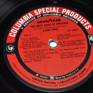 May include: A red vinyl record with the text "Columbia Special Products" and "Goodyear The Great Songs of Christmas" on a black background. The record is labeled "Side 2" and lists the songs and artists on the record. The record is part of a limited edition collectors' album.