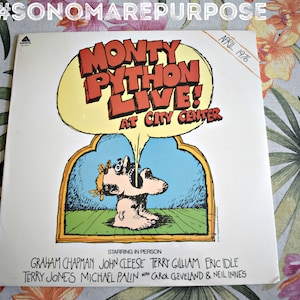 May include: A vintage record album cover featuring a cartoon illustration of a man with a large mouth, with the text "Monty Python Live! At City Center" and "April 1976". The album features the cast members: Graham Chapman, John Cleese, Terry Gilliam, Eric Idle, Terry Jones, Michael Palin, Carol Cleveland, and Neil Innes.