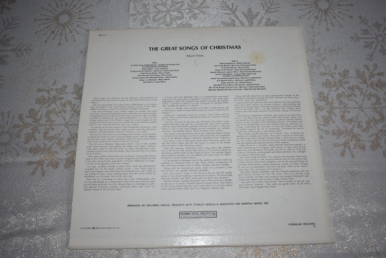 May include: The back of a vinyl record album titled "The Great Songs of Christmas". The album cover is white with black text. The album features a list of songs on each side of the record. The album is produced by Columbia Special Products with Stanley Arnold & Associates and Morriss Music, Inc.