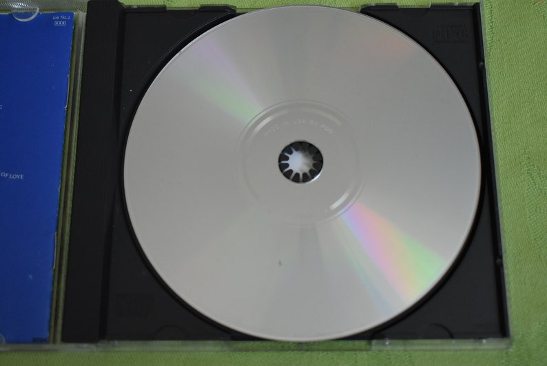 May include: A silver CD in a black jewel case. The CD has a rainbow iridescent sheen.