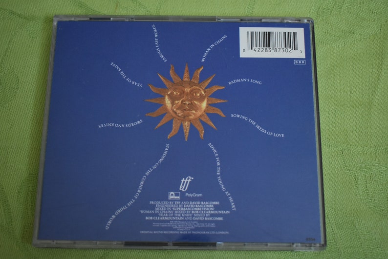 May include: A blue CD case with a sun graphic and the text "Woman in Chains" and "Badman's Song". The CD case is for the album "Standing on the Corner of the Third World" by the band "The Alarm".