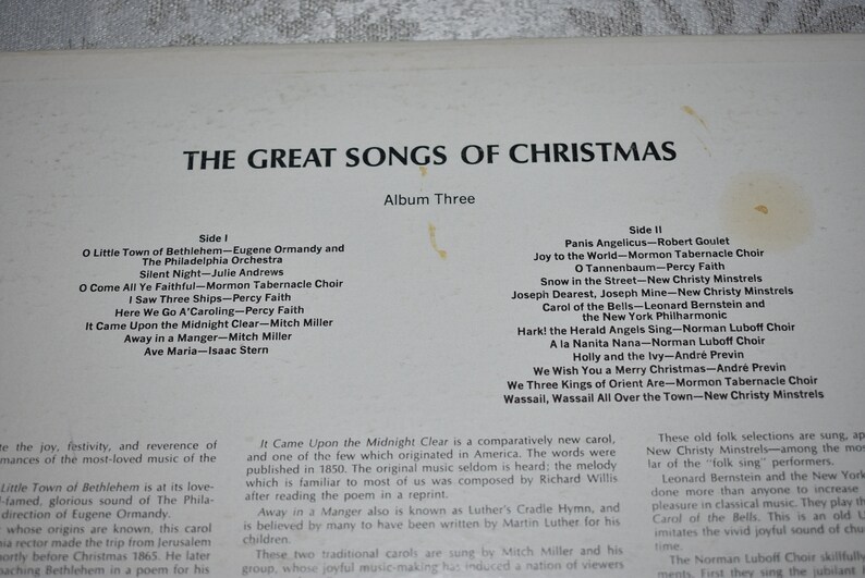 May include: A white and black album cover with the title "The Great Songs of Christmas" and a list of songs on each side of the record. The album is part of a series and is labeled "Album Three".